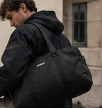 Un homme avec un sac de voyage noir en ville